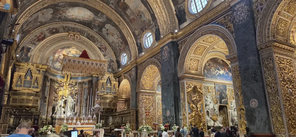 Interior barroco de la Concatedral de San Juan en La Valeta, Malta, con bóvedas doradas, frescos y capillas laterales de los Caballeros de la Orden de San Juan