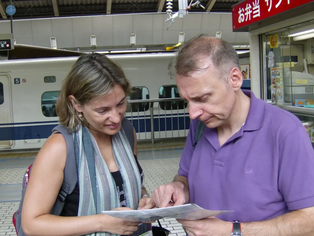 La autora del blog junto con otro viajero consultando un mapa en un andén de tren en Japón.