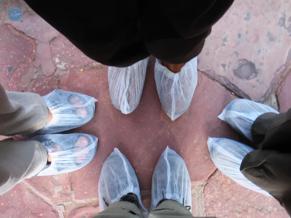 Pies con fundas desechables sobre el suelo de un templo en Agra, India