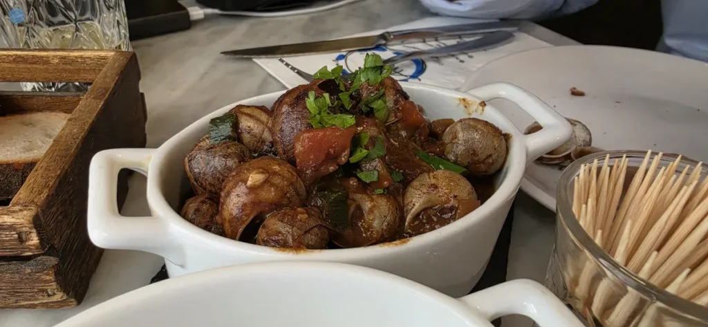 Plato de caracoles guisados con tomate y hierbas, tapa típica de la gastronomía maltesa (bebbux en maltés)