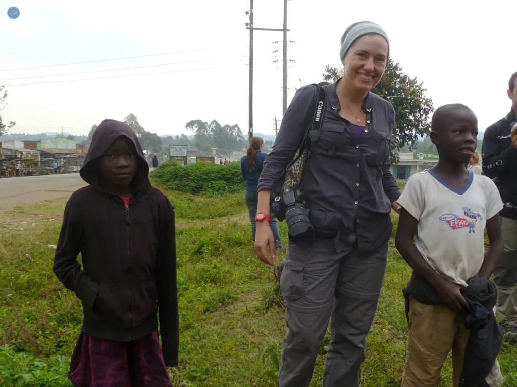 Viajera sonriente junto a dos niños en una calle de un pueblo africano