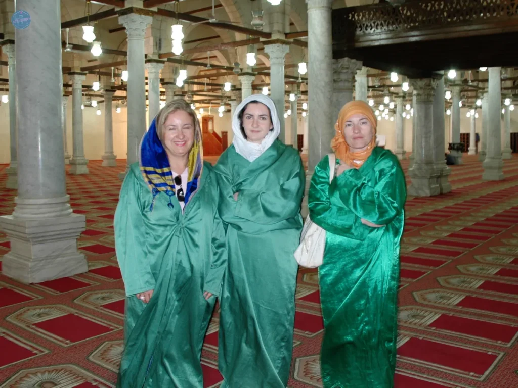 Tres viajeras cubiertas con túnicas verdes en el interior de una mezquita de El Cairo