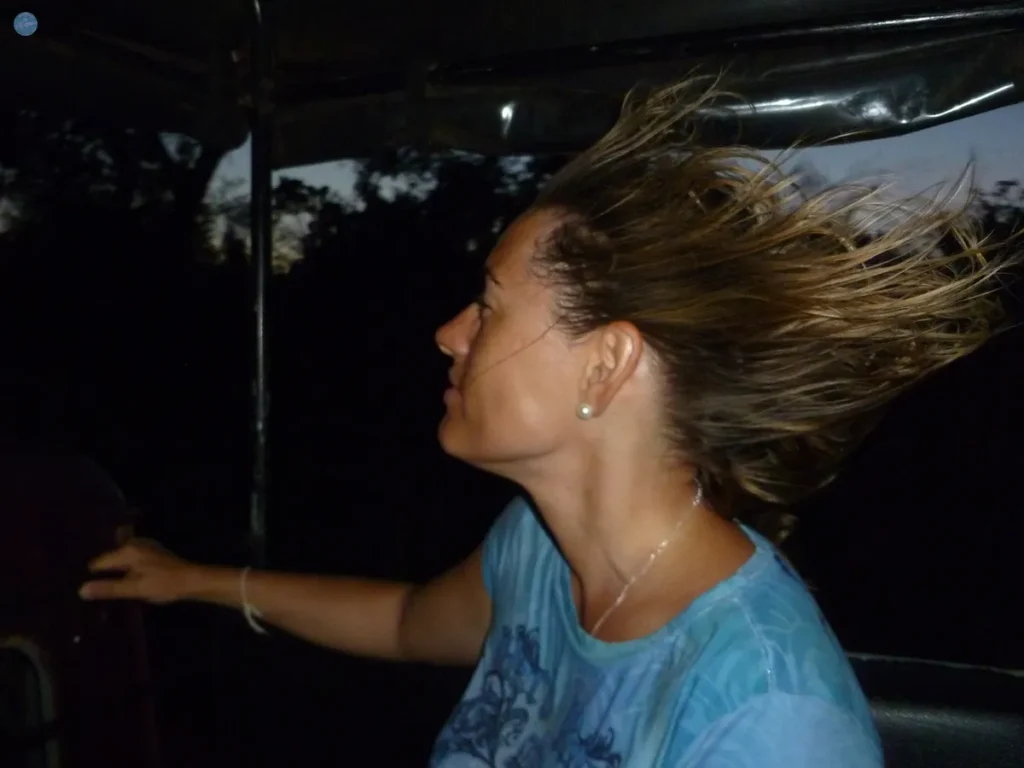 Viajera de perfil con el pelo al viento en un vehículo abierto de noche