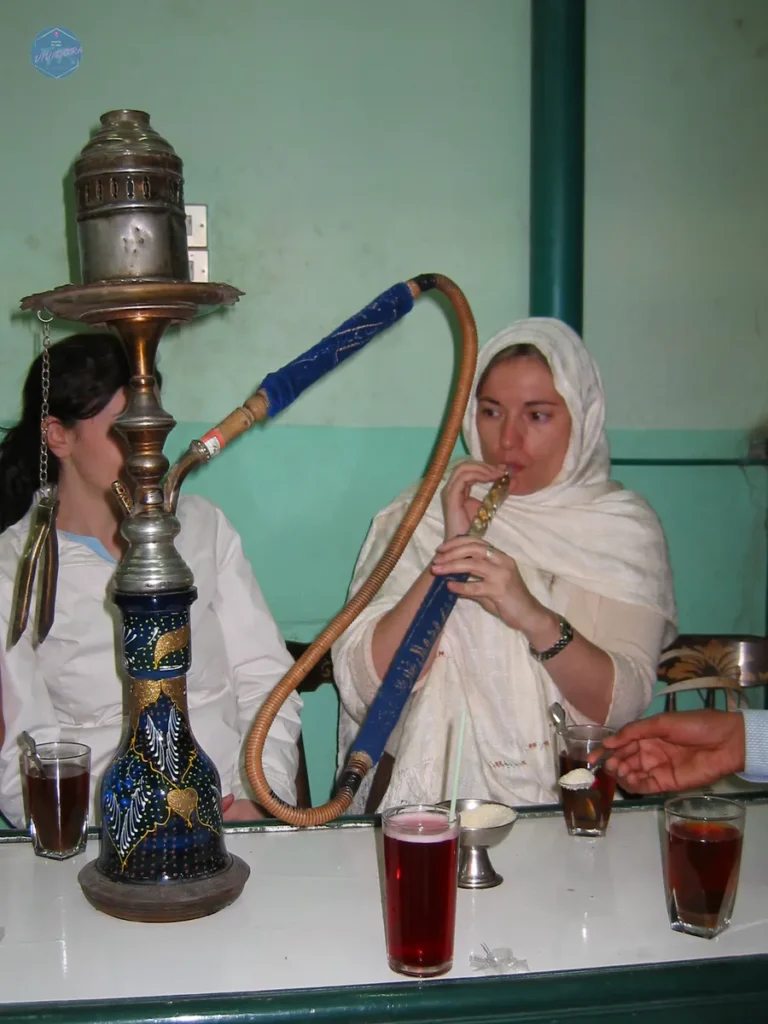 Viajera con la cabeza cubierta tomando té en un café local de Egipto